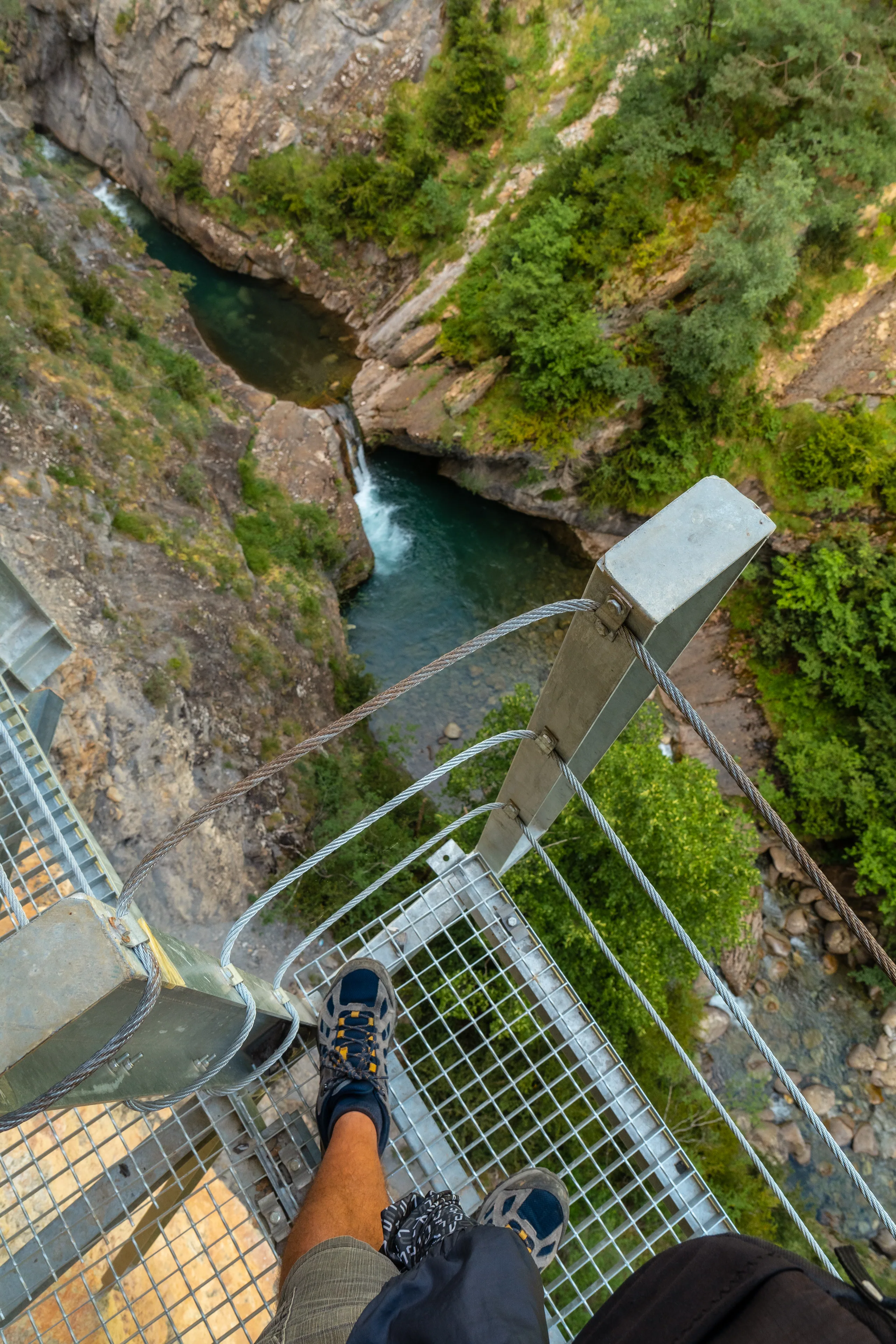 A walker crossing a swing bridge on the Hooker Valley Track with Aoraki Mt Cook in the background