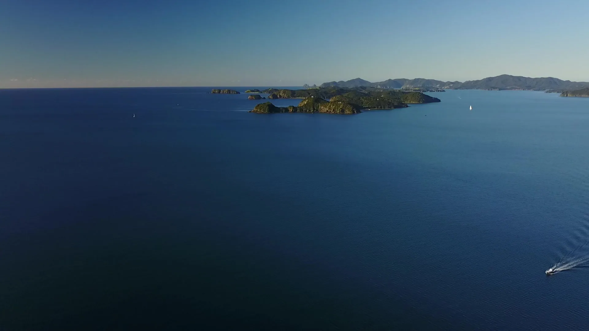 Yachts moored in turquoise water with green islands in the background