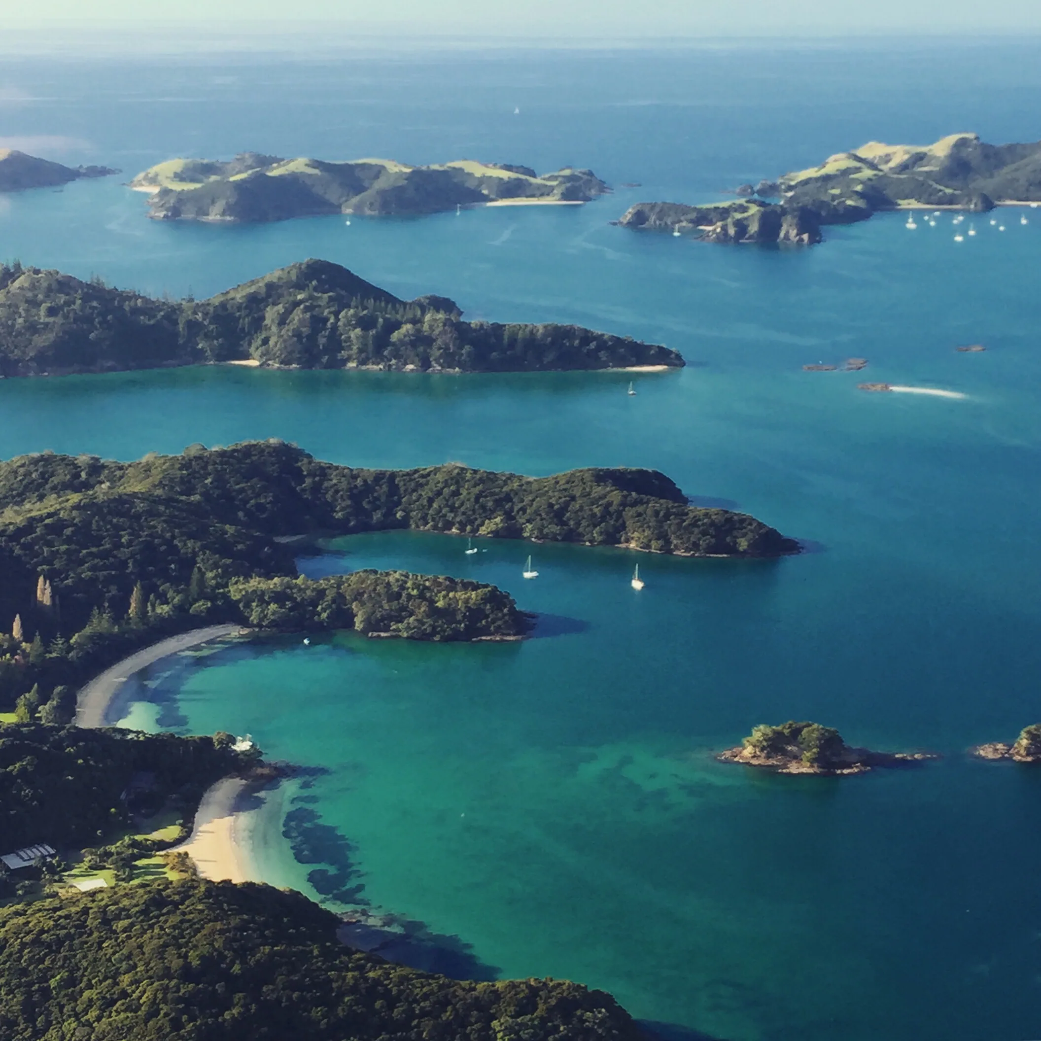 A small cruise boat passing the Hole in the Rock at Cape Brett on a sunny day