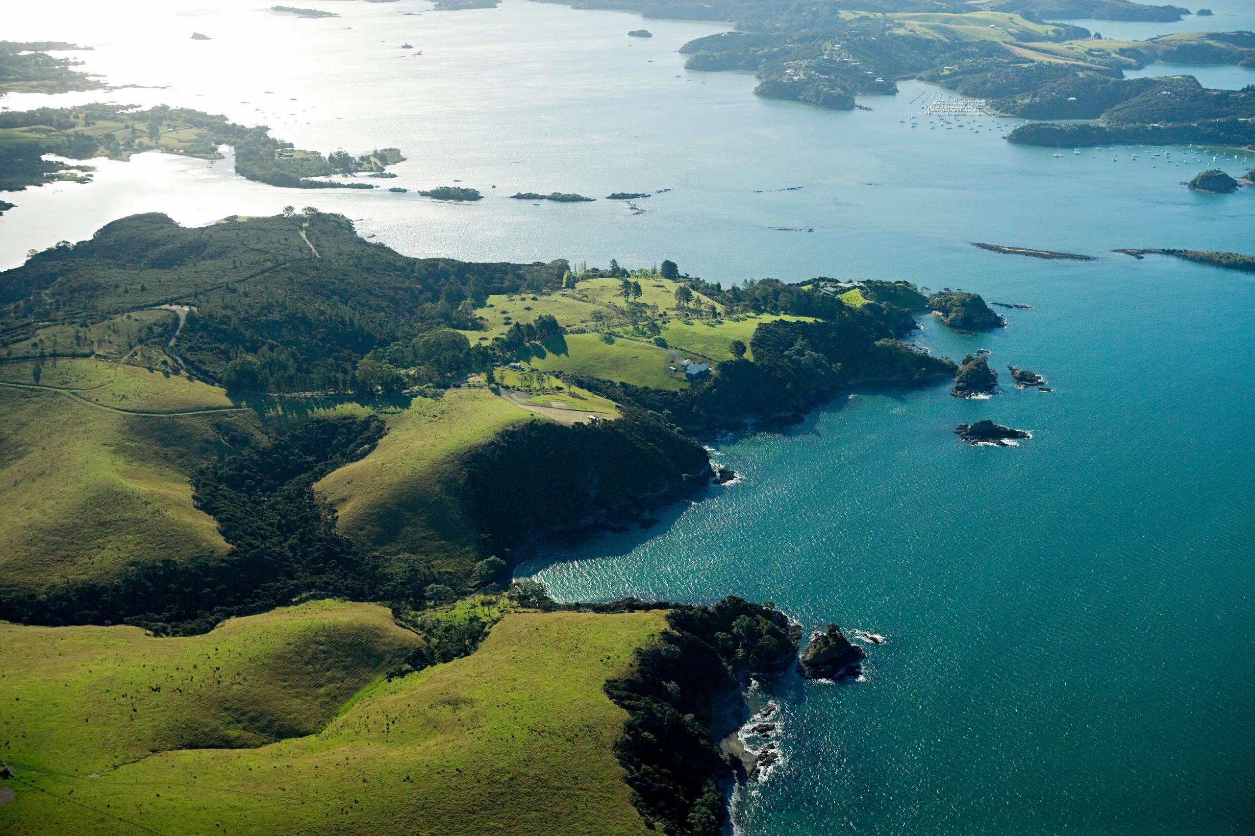 Aerial view over the Bay of Islands near Kerikeri with green headlands wrapping around blue water