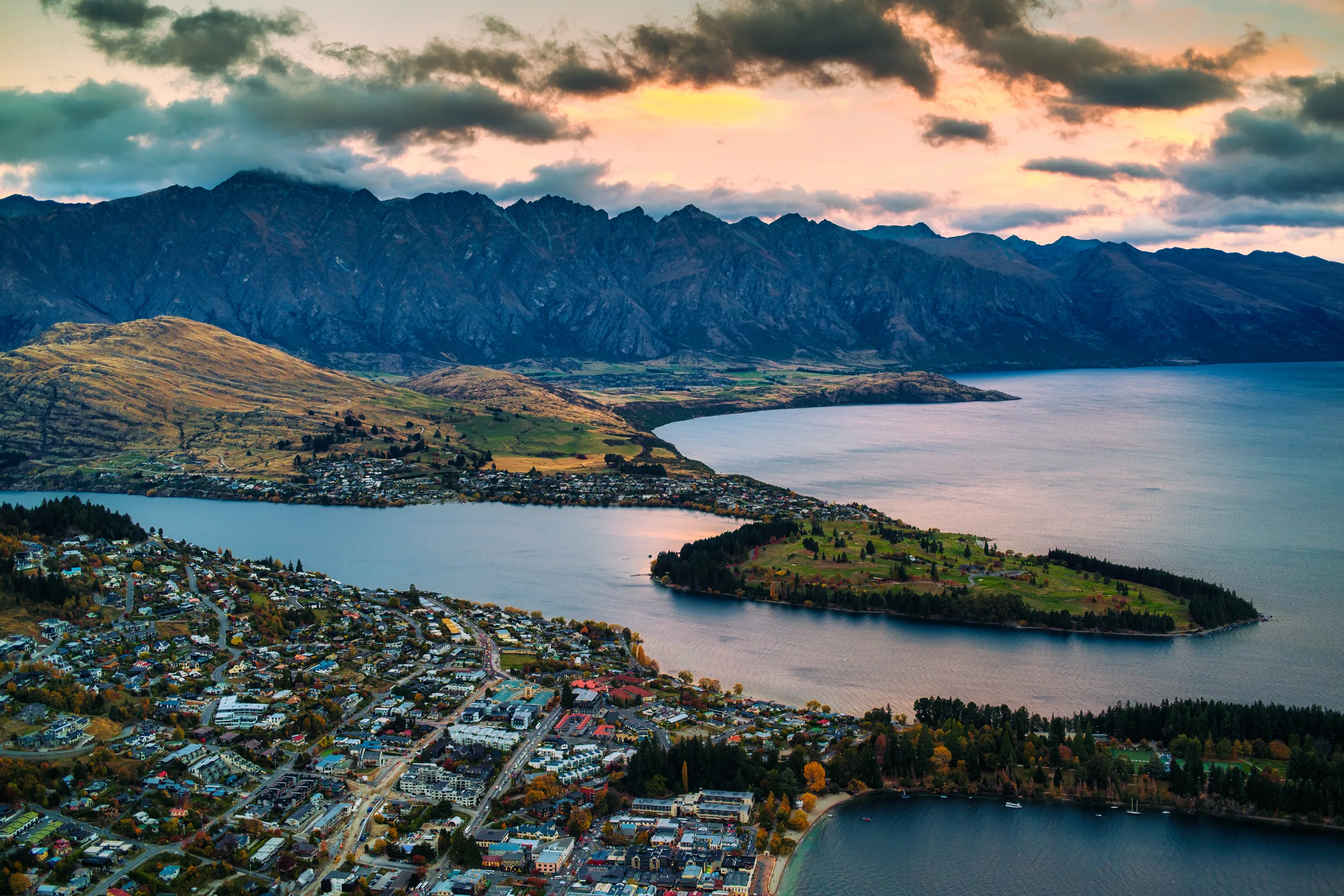 Lake Wakatipu and Queenstown in autumn with golden trees on the foreshore and the Remarkables behind