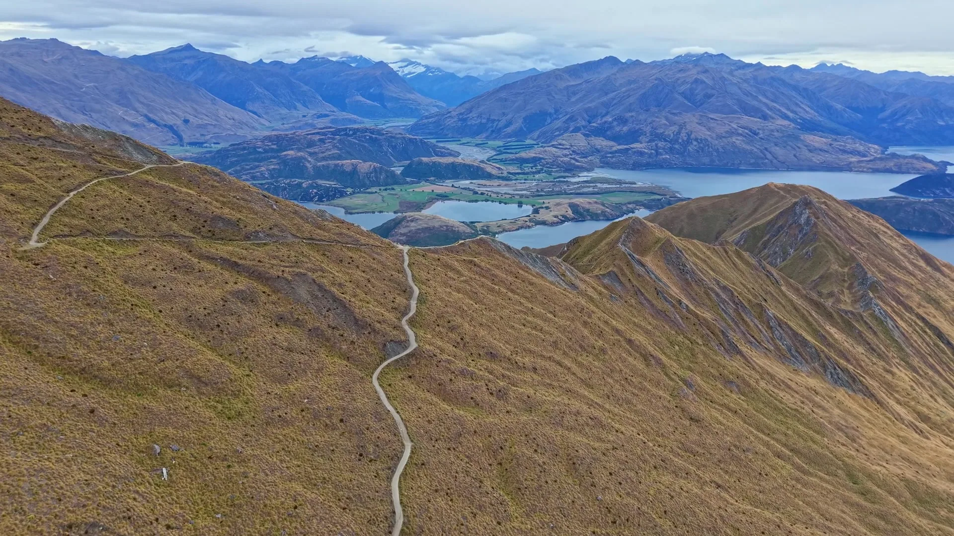 Hikers at the Roys Peak summit at sunrise with Lake Wanaka below