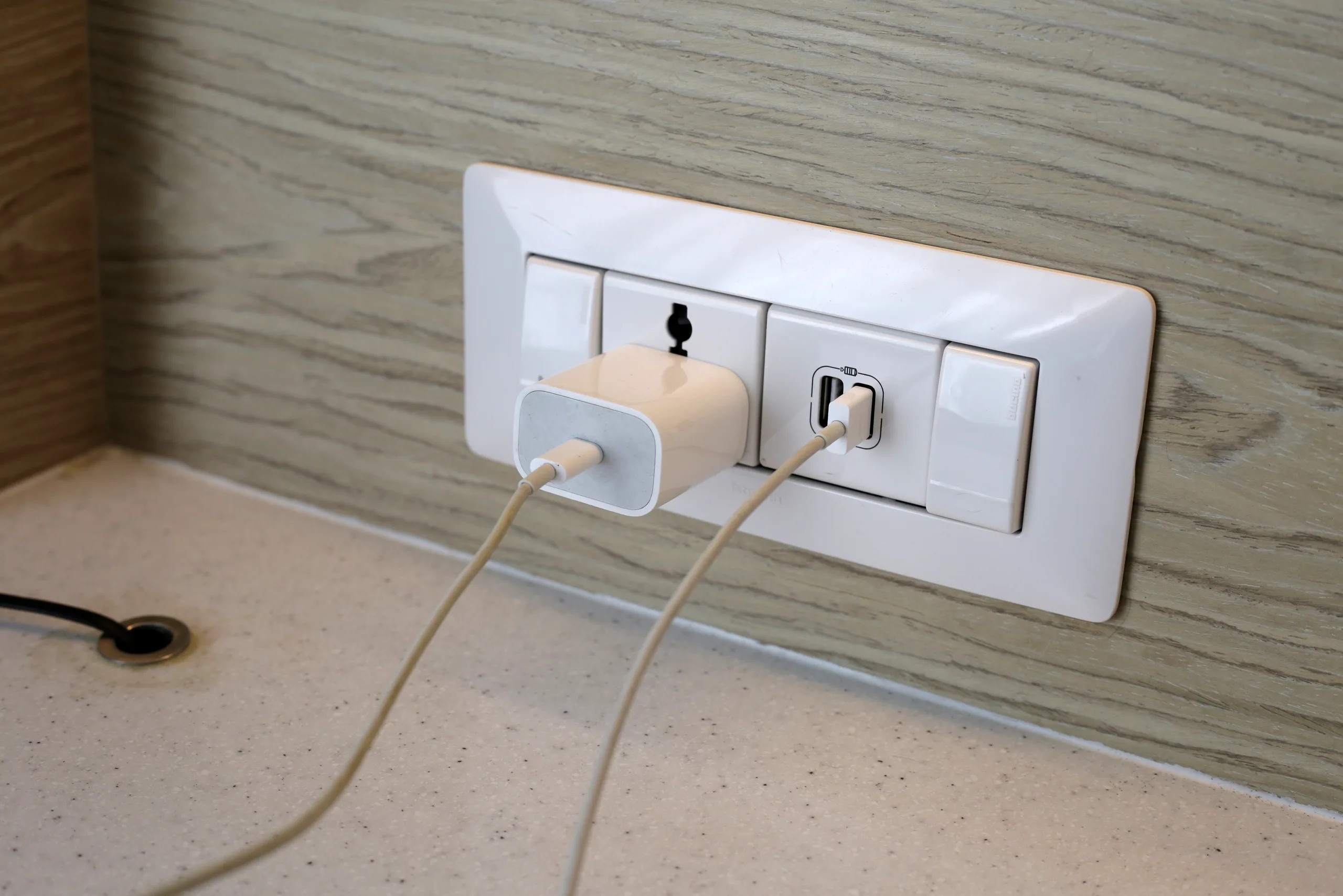 A universal travel adapter plugged into a wall socket charging multiple devices