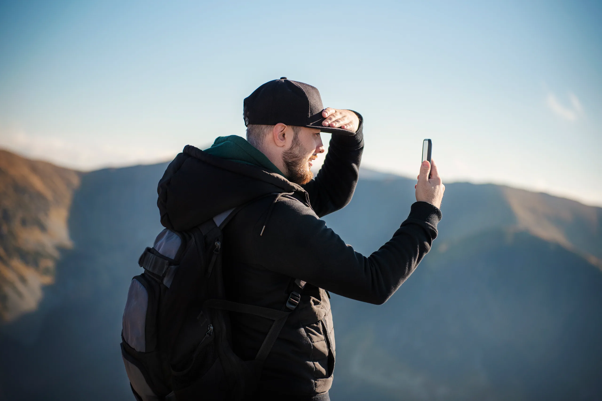 A traveller taking a smartphone photo of mountain scenery
